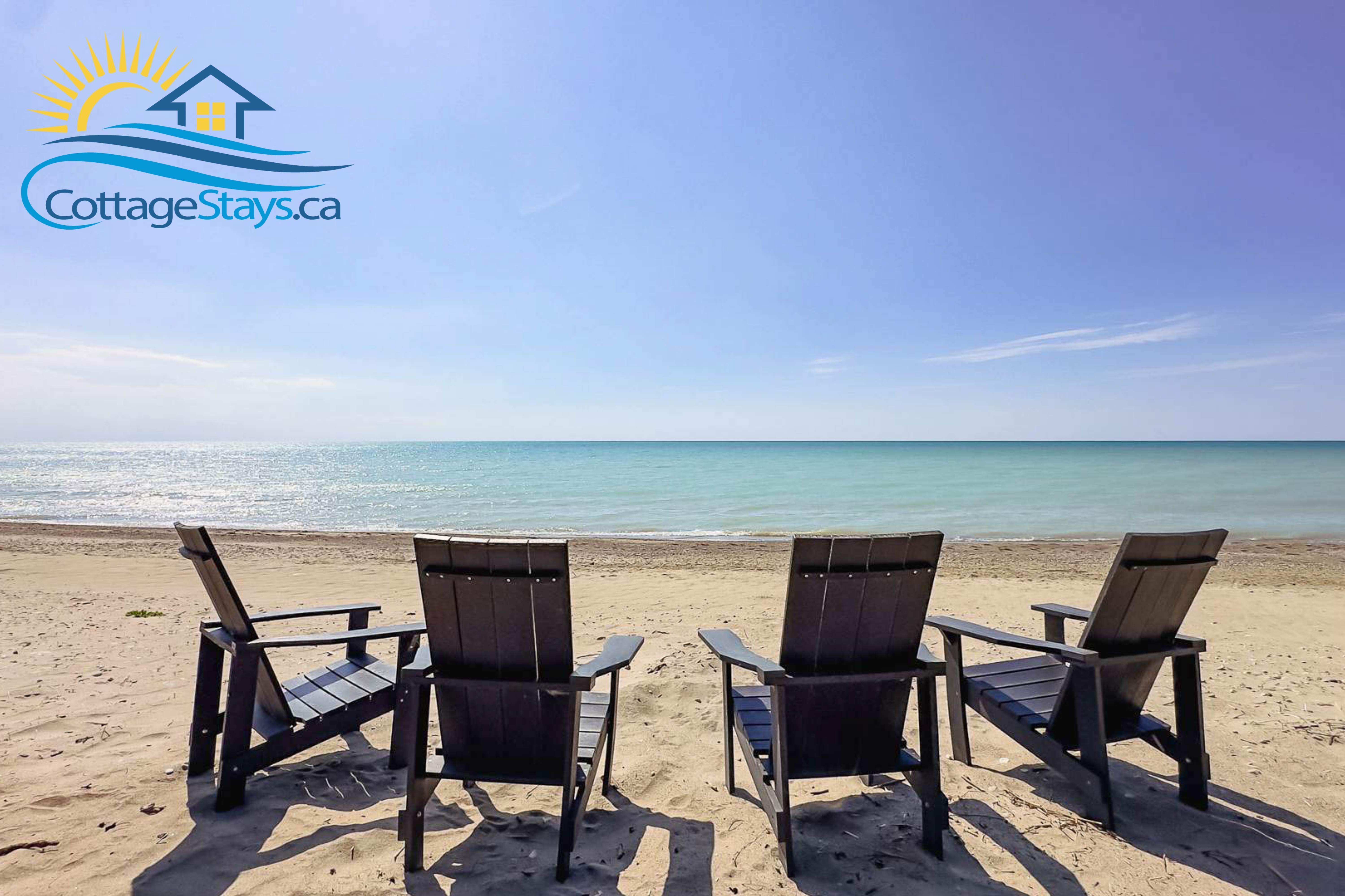 Blue water, white sand and 4 muskoka chairs on the beach